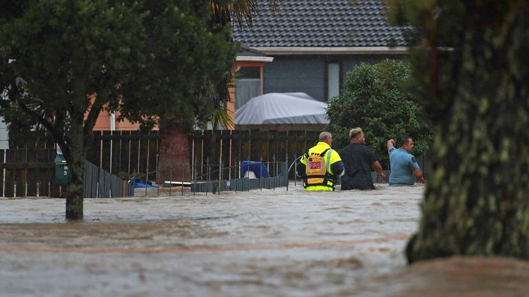 Emergency workers and a man wade through flood waters in Auckland, New Zealand 
PIC:New Zealand Herald via AP