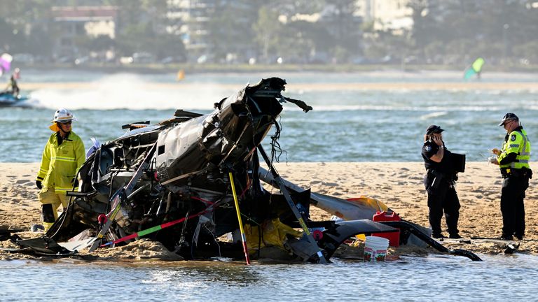 Emergency workers inspect a helicopter at a scene collision near Seaworld, on the Gold Coast, Australia, Monday, Jan. 2, 2023. Two helicopters collided killing several passengers and critically injuring a few others in a crash that drew emergency aid from beachgoers enjoying the water during the southern summer. (Dave Hunt/AAP Image via AP)