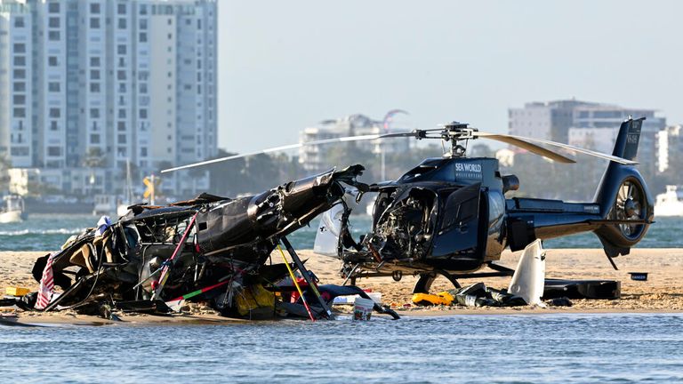 Two cashed helicopters sit on the sand at a collision scene near Seaworld, on the Gold Coast, Australia, Monday, Jan. 2, 2023. The 2 helicopters collided killing several passengers and critically injuring a few others in a crash that drew emergency aid from beachgoers enjoying the water during the southern summer. (Dave Hunt/AAP Image via AP)