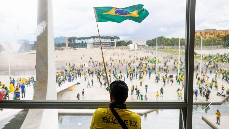 Jair Bolsonaro'nun destekçileri Brezilya Ulusal Kongresi önünde gösteri yaparken bir adam Brezilya bayrağını dalgalandırıyor