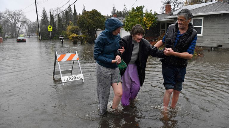 Nurse Katie Leonard, left, assists Scott Mathers, right, as they rescue Mathers&#39; mother, Patsy Costello, 88, after being trapped in her vehicle for over an hour on Astrid Drive in Pleasant Hill, California, on Saturday, Dec. 31, 2022. 