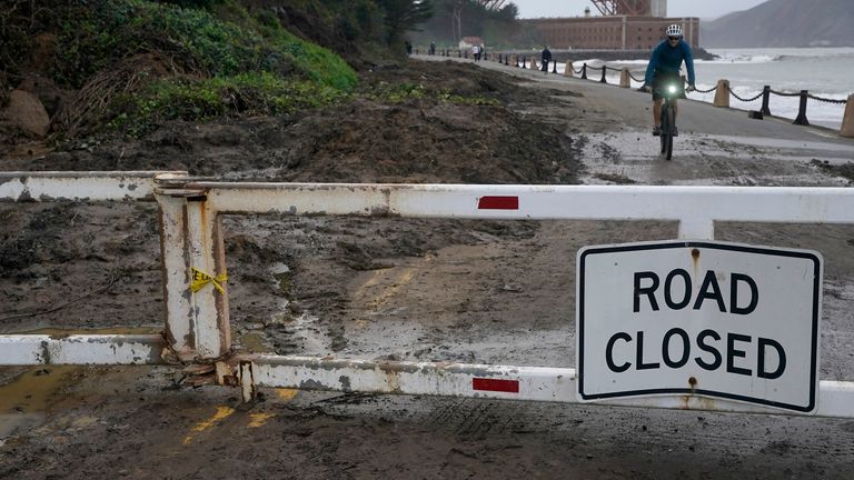 A bicyclist rides near mud and debris on a closed road near Fort Point, San Francisco.  Image: AP