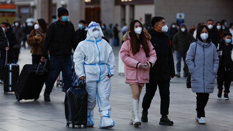 A traveller wearing a protective suit walks outside Beijing Railway Station as the annual Spring Festival travel rush starts