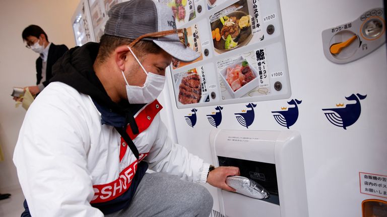 A customer buys whale meat on the opening day of a shop by a Japanese whale-hunting company with vending machines in Yokohama