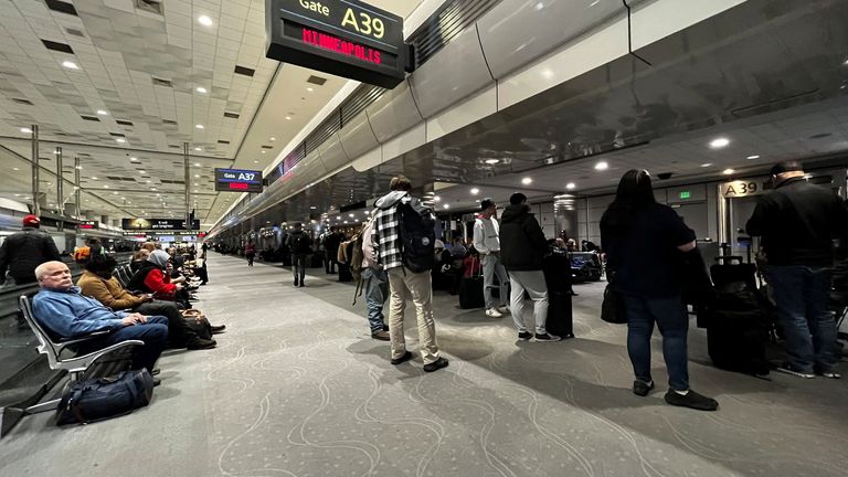 People wait at the Denver International Airport, as flights were grounded 