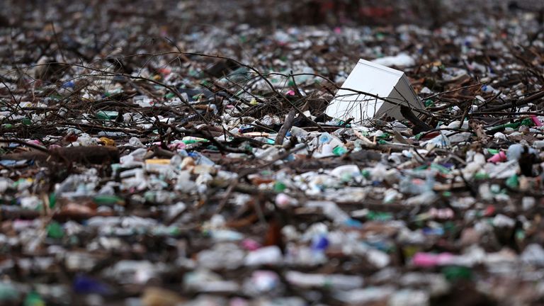 Part of a refrigerator floats among waste