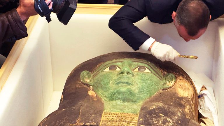 Mostafa Waziri, top official at the Supreme Council of Antiquities, takes a look with a magnifier at an ancient wooden sarcophagus during a handover ceremony at the foreign ministry in Cairo, Egypt, Monday, Jan. 2, 2023. An ancient wooden sarcophagus that was featured at the Houston Museum of Natural Sciences was returned to Egypt after U.S. authorities determined it was looted years ago, Egyptian officials said Monday. (AP Photo/Mohamed Salah)