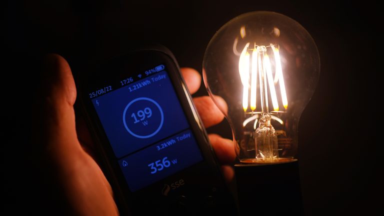 A handheld SSE smart meter for household energy usage is held next to an energy-efficient LED light bulb. Families across Great Britain will find out on Friday how tough energy bills will be this winter but they may have to wait to discover what the Government will do to help Picture date: Thursday August 25, 2022.