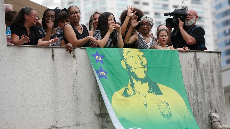 Fans are pictured with a banner as the casket of Brazilian soccer legend Pele is transported by the fire department, from his former club Santos&#39; Vila Belmiro stadium