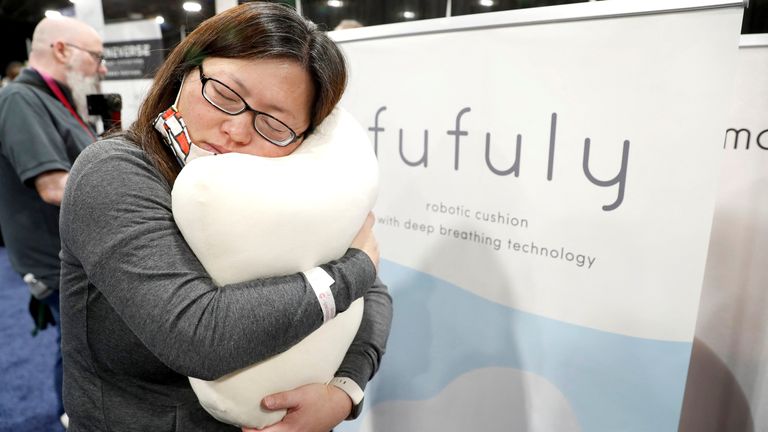 Le-Chen Cheng hugs a Fufuly, an anxiety-reducing robotic cushion by Yukai Engineering with deep breathing technology, during the CES Unveiled press event at CES 2023, an annual consumer electronics trade show, in Las Vegas, Nevada, U.S. January 3, 2023. REUTERS/Steve Marcus
