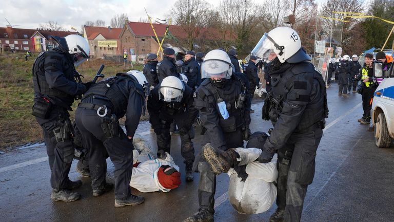 A police officers clear a blocked road at the village Luetzerath near Erkelenz, Germany, Wednesday, Jan. 11, 2023. Police have entered the condemned village in, launching an effort to evict activists holed up at the site in an effort to prevent its demolition to make way for the expansion of a coal mine. (AP Photo/Michael Probst)