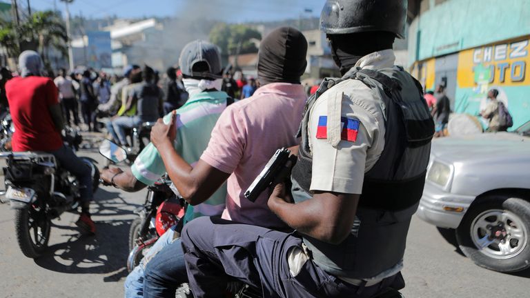 A police officer holds his gun while riding in the back of a motorcycle during a protest for the recent killings of police officers by armed gangs, in Port-au-Prince, Haiti January 26, 2023. REUTERS/Ralph Tedy Erol
