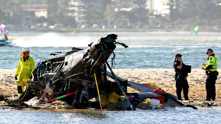Emergency workers inspect a helicopter at a scene collision near Seaworld, on the Gold Coast, Australia, Monday, Jan. 2, 2023. Two helicopters collided killing several passengers and critically injuring a few others in a crash that drew emergency aid from beachgoers enjoying the water during the southern summer. (Dave Hunt/AAP Image via AP)