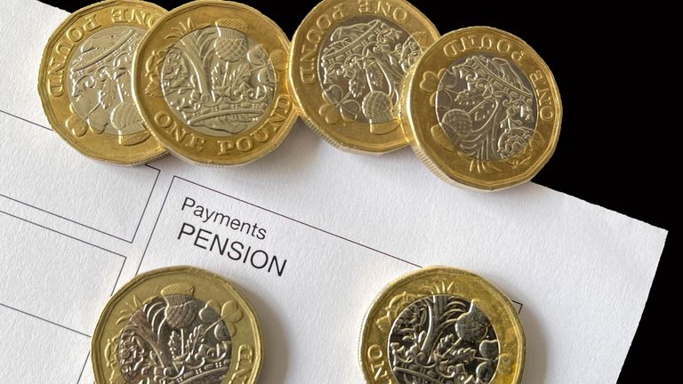 Close up view of one pound coins on top of an anonymous pension payment slip. No people. 