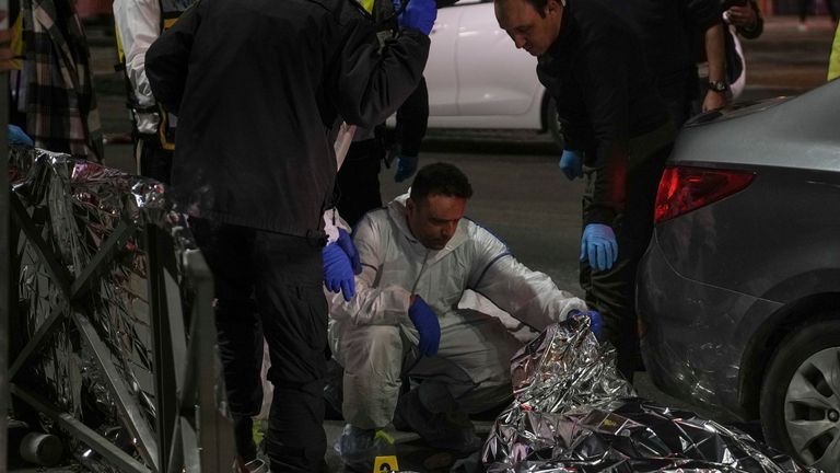 Forensic experts check a body. Pic: AP