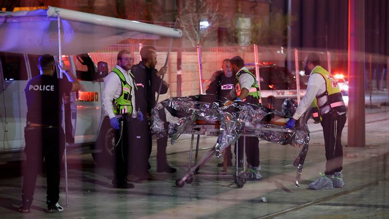 Israeli security forces move a body as they work at the scene of the shooting in Neve Yaakov