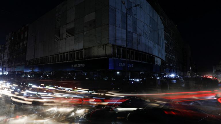 Pakistan'ın Karaçi kentinde 23 Ocak 2023'te ülke çapında elektrik kesintisi sırasında araç ışıkları bir pazar boyunca yolda hafif çizgilere neden oluyor. REUTERS/Akhtar Soomro