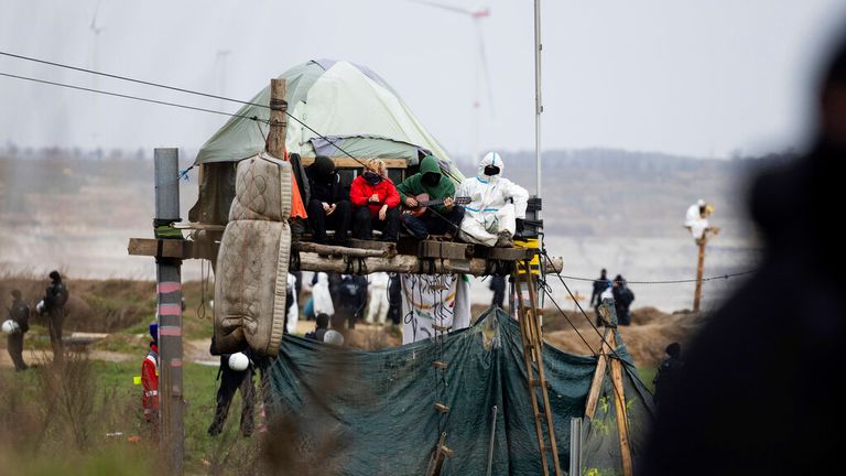 Environmental activists sit on a makeshift platform on stilts near the edge of the demolition of the Garzweiler II open-pit lignite mine in Luetzerath, Germany, Thursday Jan. 5, 2023. Police say they have again crossed a barricade for security reasons at the occupied village of Luetzerath.  The village of Luetzerath is abandoned by its inhabitants but occupied by opponents of lignite mining to protest against the continued expansion of fossil fuels.  (Rolf Vennenberg/dpa via AP).  Photo: AP