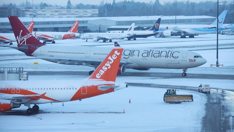 Snow ploughs clear snow from the airfield after overnight snow forced the closure of Manchester airport, in Manchester, Britain, January 19, 2023. REUTERS/Phil Noble
