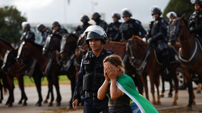 A woman reacts next to members of the army as supporters of former Brazilian President Jair Bolsonaro leave a camp outside the army headquarters, in Brasilia, Brazil