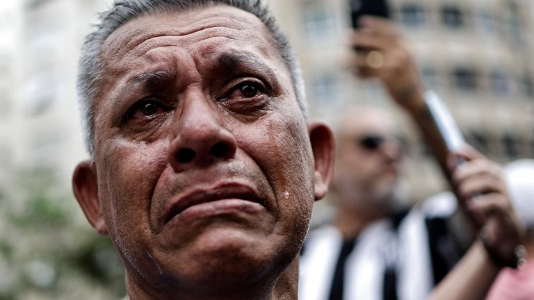  A mourner reacts as Brazilian soccer legend Pele is transported by the fire department, from his former club Santos&#39; Vila Belmiro stadium 