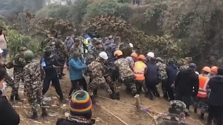 Recovery workers pull on ropes in Nepal at the site of a fatal plane crash