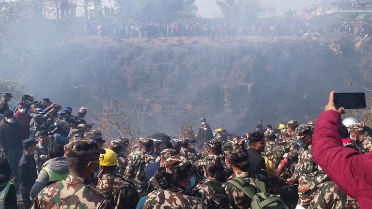 Crowds gather as rescue teams work to retrieve bodies at the crash site