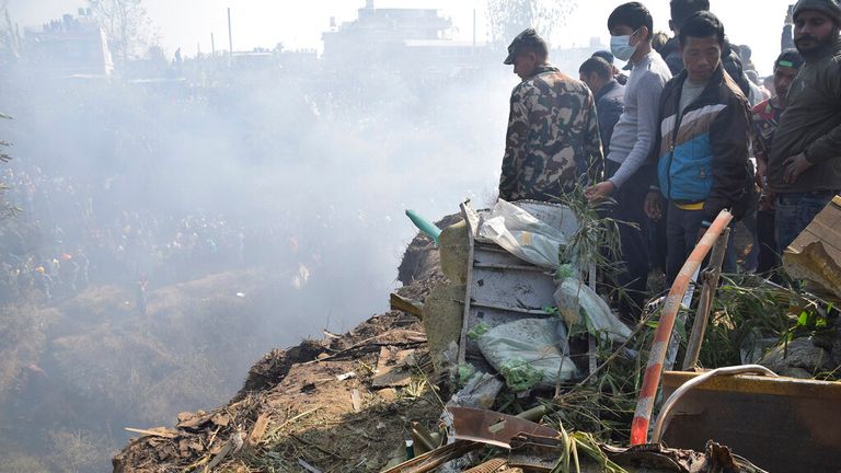 Nepalese rescue workers and civilians gather around the wreckage. Pic: AP
