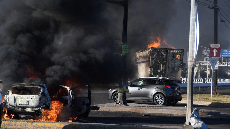 Burning vehicles block a road after Ovidio Guzman was captured