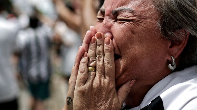 A mourner reacts as Brazilian soccer legend Pele is transported by the fire department, from his former club Santos' Vila Belmiro stadium