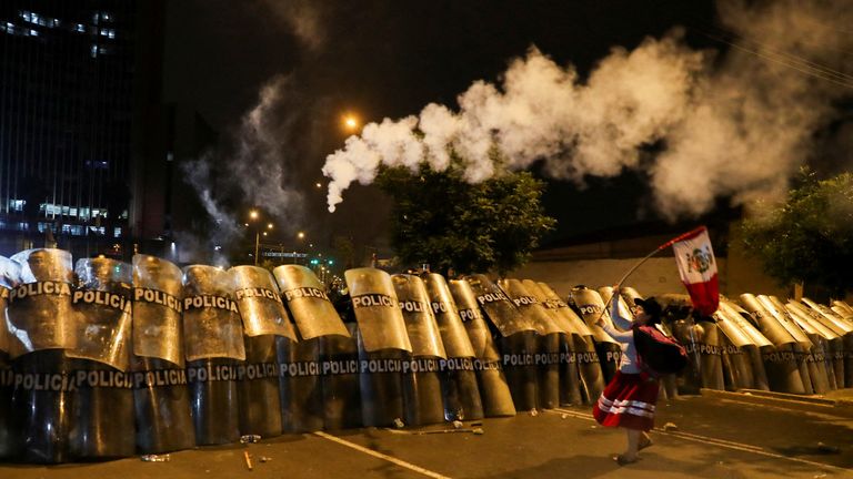 A woman waves a Peruvian flag in front of riot police during the &#39;Take over Lima&#39; march to demonstrate against Peru&#39;s President Dina Boluarte, following the ousting and arrest of former President Pedro Castillo, in Lima, Peru January 20, 2023. REUTERS/Sebastian Castaneda TPX IMAGES OF THE DAY