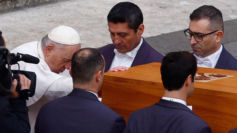 Pope Francis touches the coffin of former Pope Benedict 