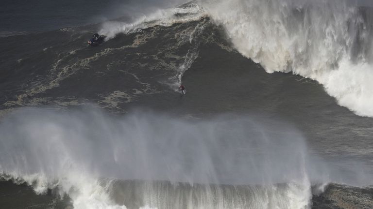 FILE PHOTO: A surfer catches a wave in Praia do Norte, Nazare, Portugal on February 25, 2022.  REUTERS/Pedro Nunes/File photo