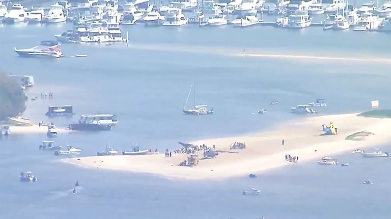 This image made from video shows a sandbar with a crashed helicopter on the Gold Coast, Australia, Monday, Jan. 2, 2023. Two helicopters collided over the Australian beach on Monday afternoon.  (Australian Broadcasting Corp. via AP)