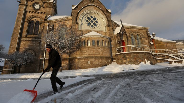A man clears snow at the Church of Scotland in Pitlochry