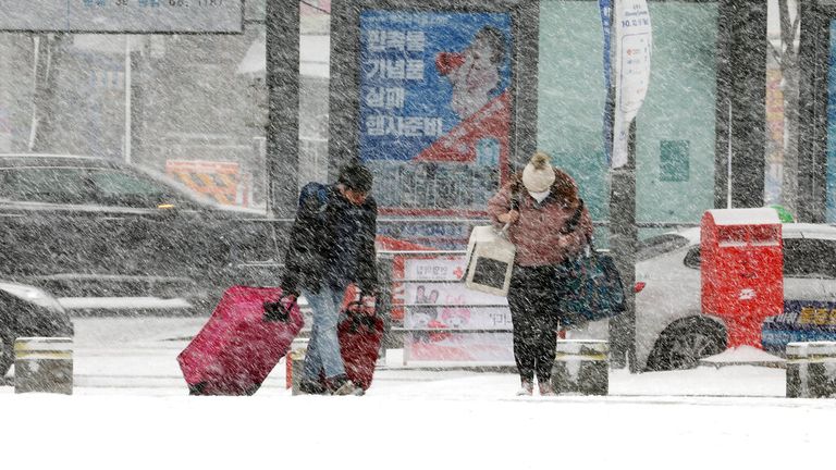 People head to a bus station amid heavy snowfall in Gwangju, South Korea. Pic: Chun Jung-in/Yonhap via AP