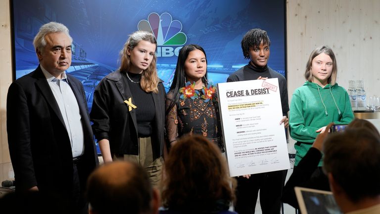 Climate activists Greta Thunberg of Sweden, Vanessa Nakate of Uganda, Helena Gualinga of Ecuador and Luisa Neubauer of Germany, from right, stand together with a notice to Fossil Fuel CEOs, beside Fatih Birol, Head of the International Energy Agency, left, after a press conference at the World Economic Forum in Davos, Switzerland Thursday, Jan. 19, 2023. The annual meeting of the World Economic Forum is taking place in Davos from Jan. 16 until Jan. 20, 2023. (AP Photo/Markus Schreiber)