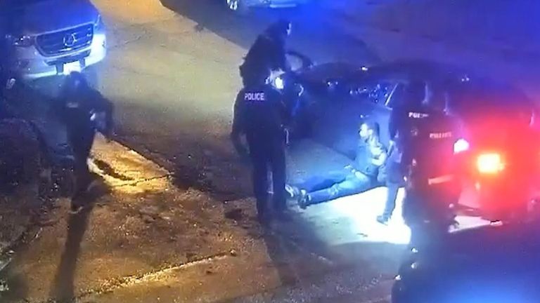 Officers stand around as Tyre Nichols is slumped against a car.