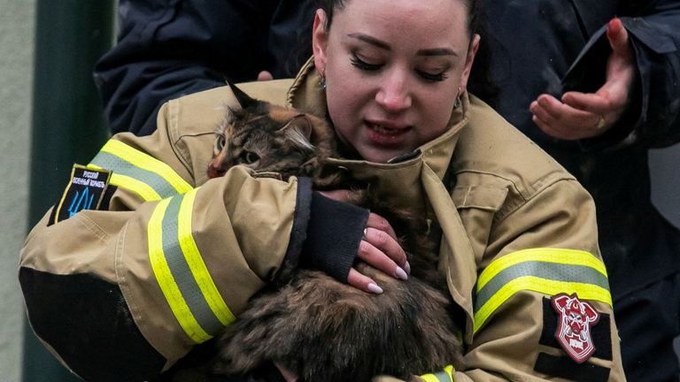 An emergency worker holds a cat rescued from the ruins of a Dnipro apartment block.