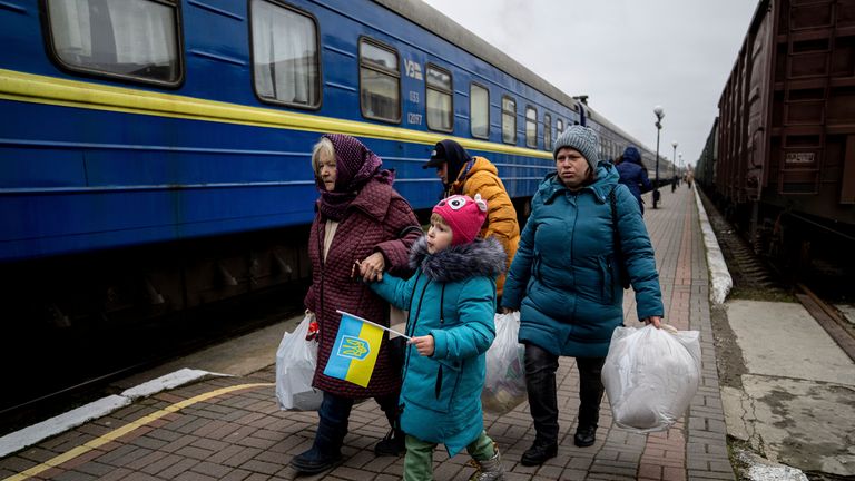 Natalia Korsh, 72, left, Veronika Korsh, 5, and Oksana Korsh, 39, right, walk along the platform to take the evacuation train in Kherson, Ukraine, Thursday, Dec. 1, 2022. Four members of the family decided to go to Kyiv after their house was damaged by Russian shelling. (AP Photo/Evgeniy Maloletka)