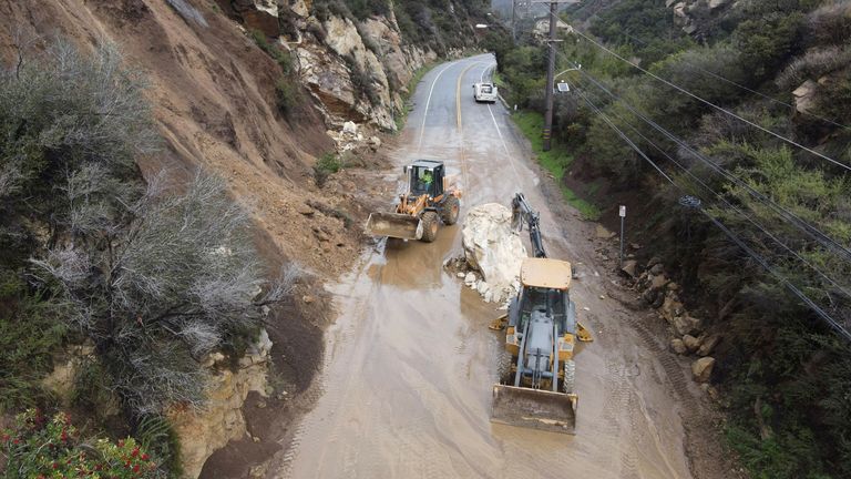 CalTrans workers chip away at a huge boulder that fell on Malibu Canyon Road in Malibu, California
