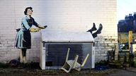 The new works by Banksy, appears to show a 1950&#39;s housewife, wearing a classic blue pinny and yellow washing up gloves, with a swollen eye and a missing tooth seemingly shoving her male partner into a chest freezer, the piece is set on a white wall backdrop in Kent. Issue date: Tuesday February 14, 2023.