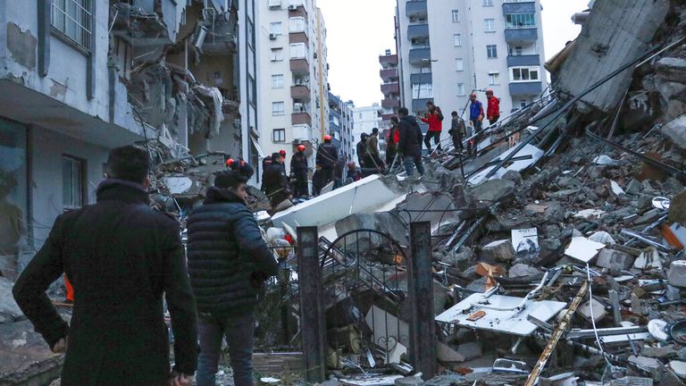 People and rescue teams try to reach trapped residents inside collapsed buildings in Adana in Turkey. Pic: AP