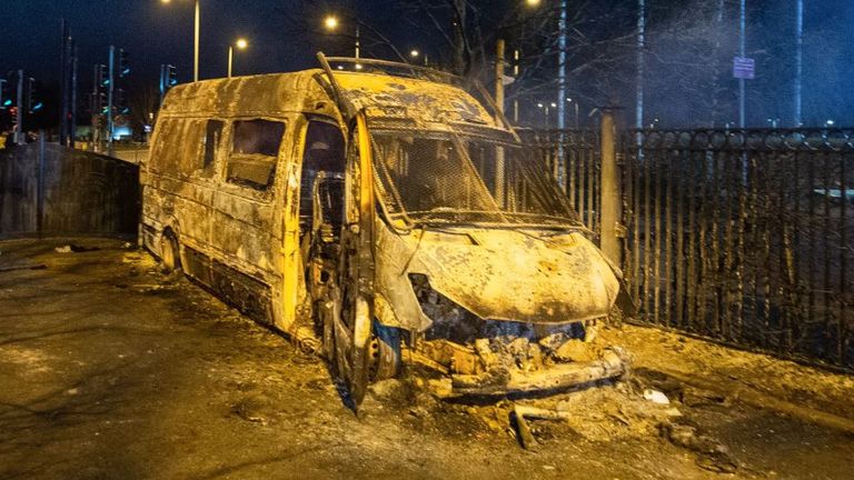 A burnt out police van after a demonstration outside the Suites Hotel in Knowsley