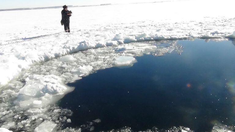 A Russian policeman works near an ice hole, said by the Interior Ministry department for Chelyabinsk region to be the point of impact of a meteorite seen earlier in the Urals region, at lake Chebarkul some 80 kilometers (50 miles) west of Chelyabinsk February 15, 2013. The meteorite streaked across the sky and exploded over central Russia on Friday, sending fireballs crashing to earth which shattered windows and damaged buildings, injuring more than 500 people. REUTERS/Chelyabinsk region Interi