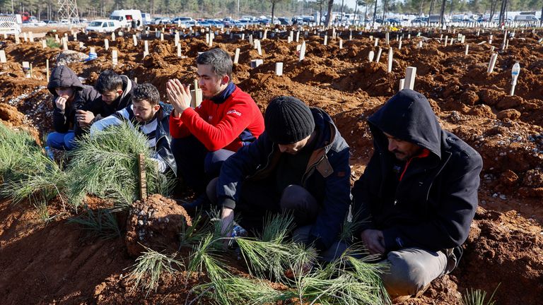 People react next to graves of victims of the deadly earthquake, in a cemetery in Kahramanmaras, Turkey 