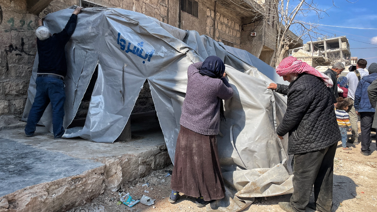 A family puts up a tent after their home was destroyed in the quake