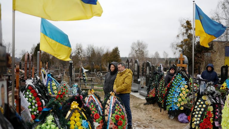 People visit the graves of their relatives, Ukrainian service members killed in fights against Russian troops, on a day of the first anniversary of Russia&#39;s attack on Ukraine, at a cemetery in the town of Bucha, outside Kyiv, Ukraine February 24, 2023.  REUTERS/Valentyn Ogirenko.