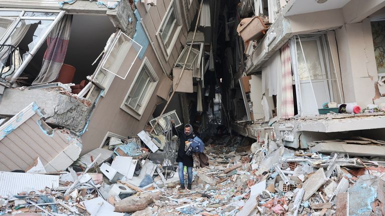 A survivor walks carrying belongings salvaged from his destroyed home, in the aftermath of a deadly earthquake in Hatay, Turkey February 9, 2023. REUTERS/Umit Bektas
