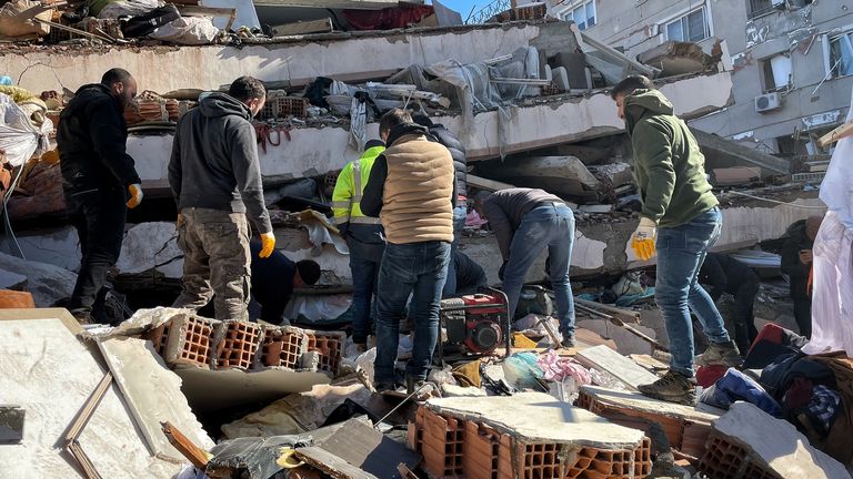 İnsanlar, Türkiye'nin güneyindeki Hatay'da meydana gelen yıkıcı depremin ardından çöken bir binanın molozlarını temizlemeye çalışıyor.  Alex Crawford raporu için.